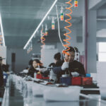 Women manufacturing electronic devices in factory.