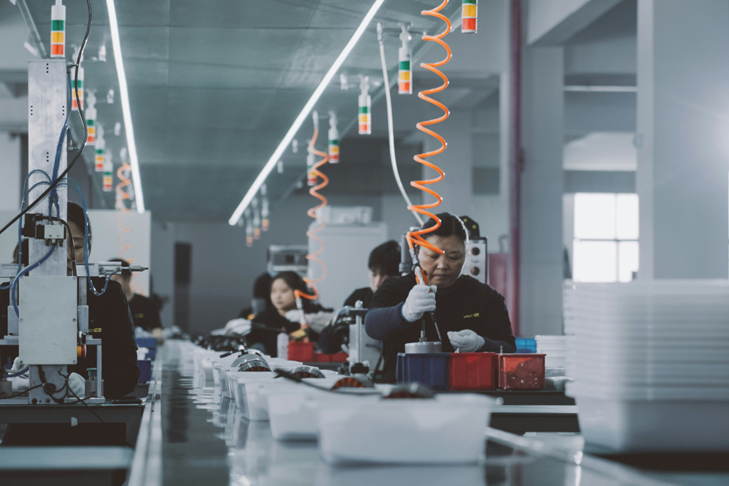 Women manufacturing electronic devices in factory.